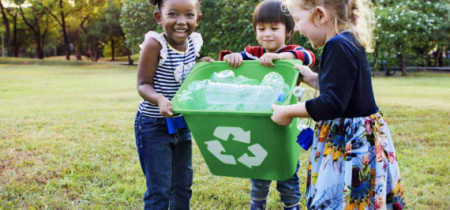 Children holding a full recycling bin outside