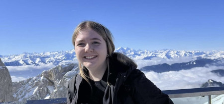Young woman standing outside in front of a scenic view with mountains