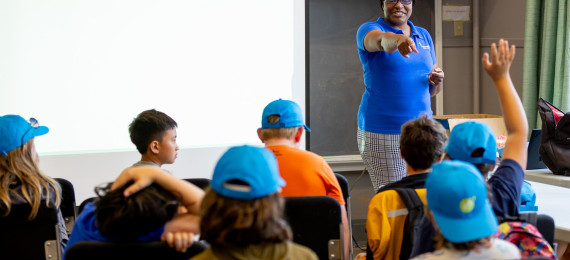 educator in classroom pointing at student with hand up