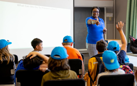 educator in classroom pointing at student with hand up