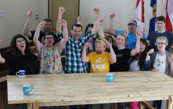 A group of people standing behind a wooden table
