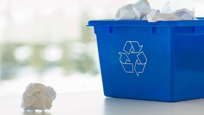 a recycling bin overflowing with crunched up paper