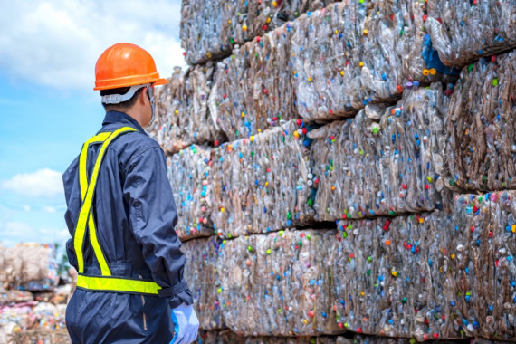 a person in safety gear looking at cubes of recycling