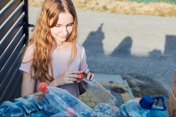 a girl holding an empty plastic bottle 