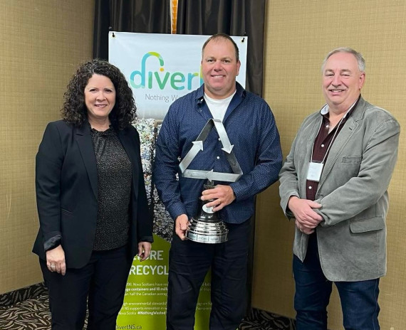 award winner accepting his award with 2 divert ns staff