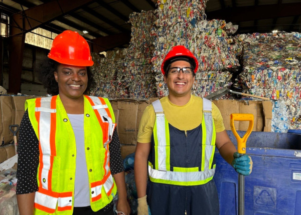 2 people smiling infront of recycling