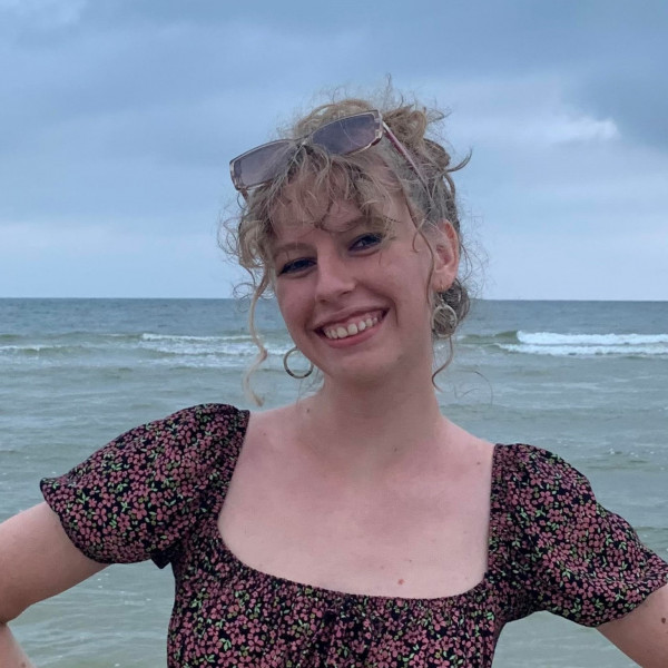 girl smiling at the beach with hands on her hips